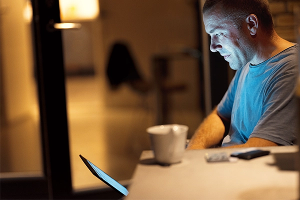 En mand kigger på sin computer og pensionsopsparing i aftenlysets skær